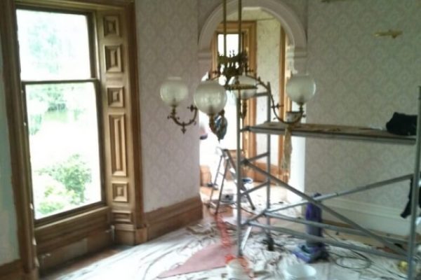 room with painting stripping in progress, natural wood window surrounds stripped of paint