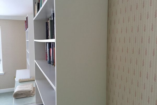 bookcase against a wall with new cream coloured wallpaper. Wallpaper features vertical lines, occasionally interrupted by thick squiggles pattern at regular intervals
