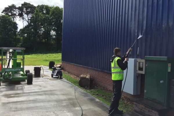 Worker in the middle of painting industrial building in dark blue