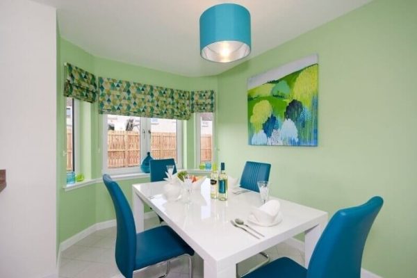 bright greed painted wall and blue leather chairs with colorful paintings and blinds